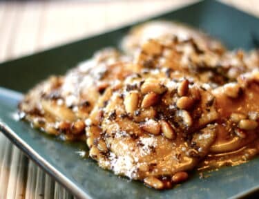 Plate of butternut squash ravioli with a buttery brown sugar sauce, parmesan cheese, toasted pine nuts, and chocolate shavings