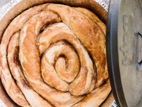 Een Cinnamon Roll gebakken in een Dutch Oven met het Dutch Oven deksel op de kant