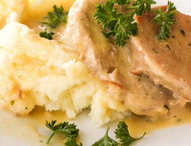 Pork chops made in the Crock Pot on a plate with sauce and mashed potatoes