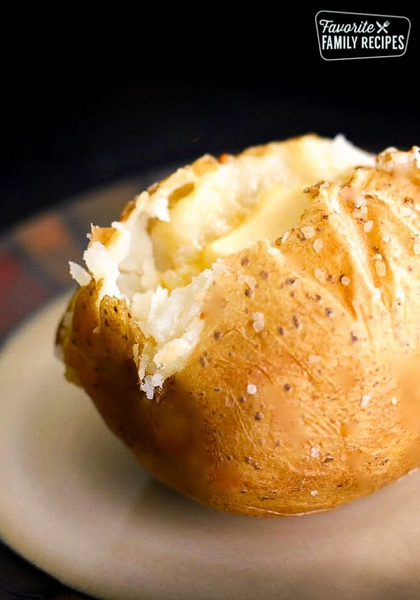 Pomme de terre cuite au four, ouverte par craquage, sur une assiette blanche