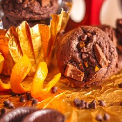 Chocolate orange cookies with an orange peel and chocolate shavings on the side.