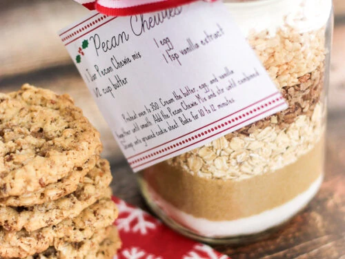 Un piatto di biscotti con un barattolo di Pecan Chewies Mix in un mason jar a lato