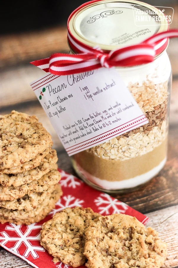 Un plato de galletas con un tarro de Pecan Chewies Mix en un tarro de cristal al lado