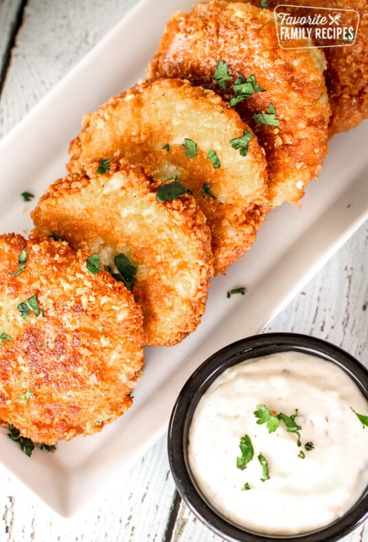 Crab Cakes lined on a white tray with Homemade Tartar Sauce on the side.