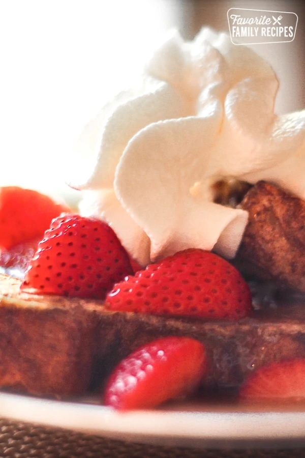 Nahaufnahme von Knetern French Toast mit Erdbeeren, Schlagsahne und Karamellsirup