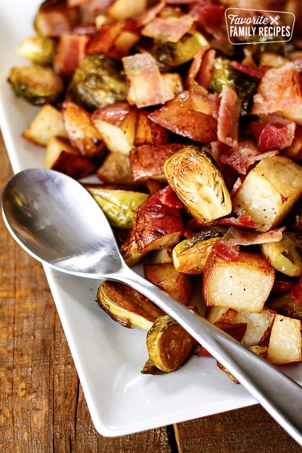 Assiette blanche avec pommes de terre et choux de Bruxelles rôtis et cuillère en argent