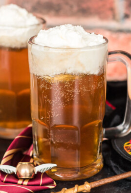 Two glass mugs of Harry Potter Butterbeer with creamy foam on top.