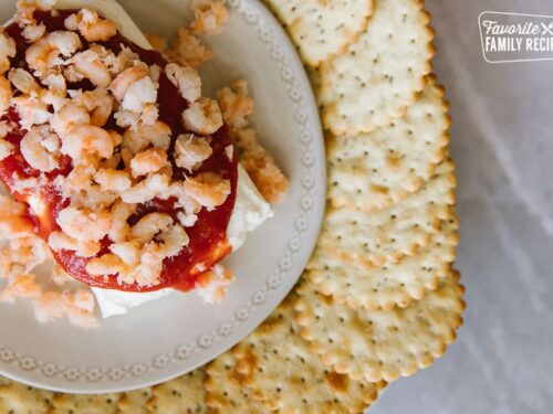 Frischkäse-Garnelen-Dip auf einem weißen Teller, umgeben von Crackern