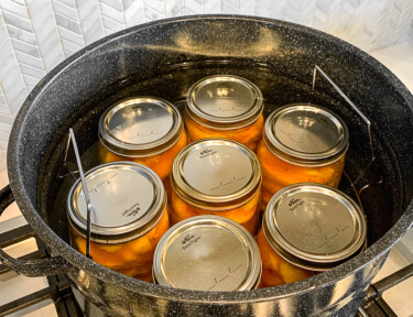 Glass jars filled with peaches in a water bath canner