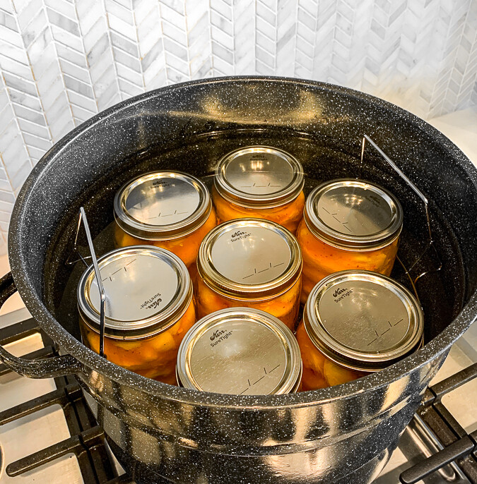 Glass jars filled with peaches in a water bath canner