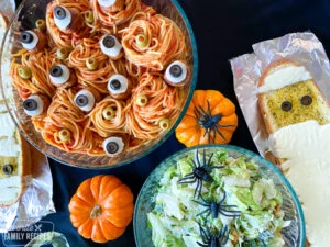 Halloween-Spaghetti in einer Schüssel mit Salat und käsigem Knoblauchbrot