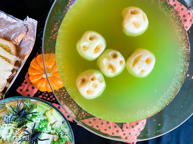 Groene punch met appels die eruit zien als gekrompen hoofden