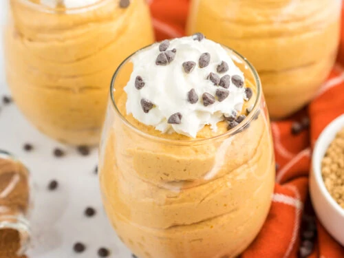 Tres tazas de mousse de calabaza cubierto con crema batida y chispas de chocolate