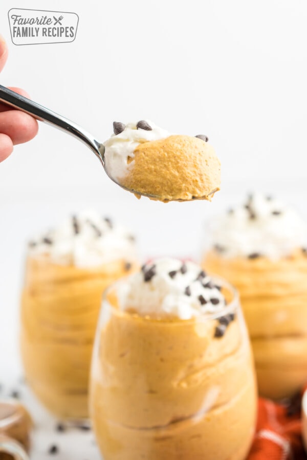 A spoonful of pumpkin mousse spooned from a parfait cup of pumpkin mousse