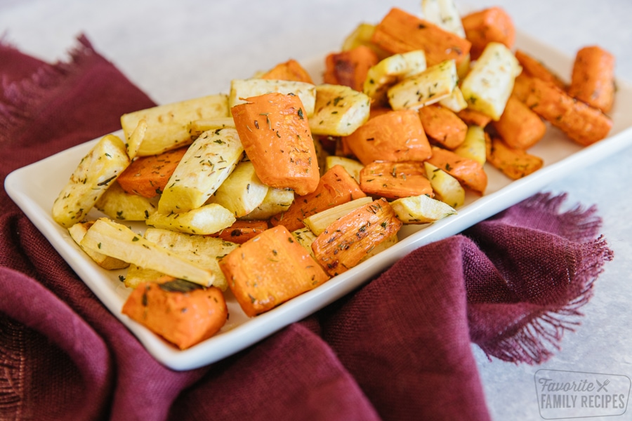 A white tray filled with roasted parsnips and carrots.