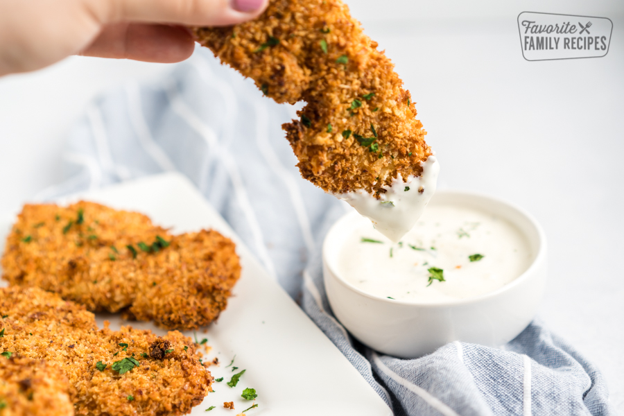 A chicken tender being dipped in ranch