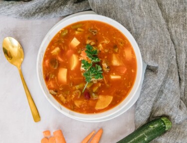 Weight loss magic soup in a bowl with carrots and zucchini on the side.