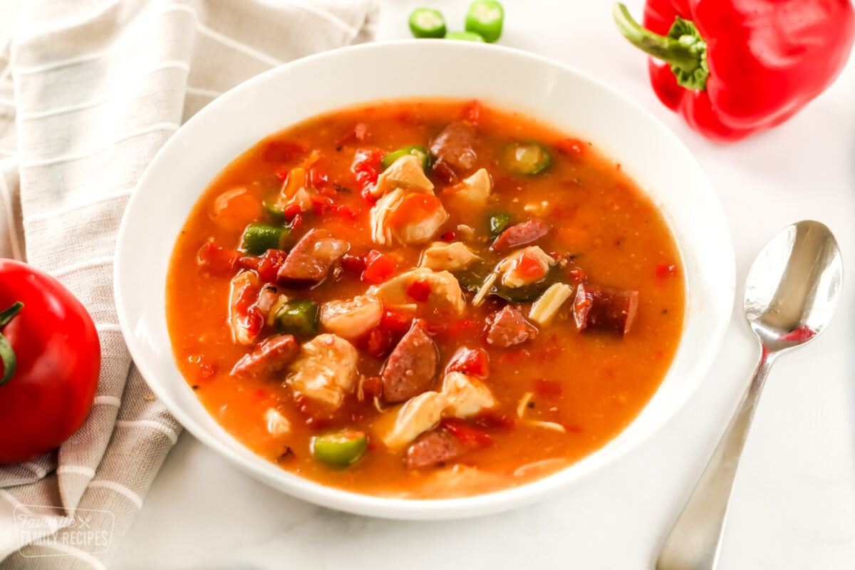 Bowl of Instant Pot Gumbo in a bowl with a tomato and pepper on the side