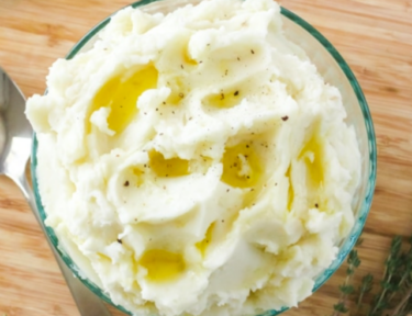 A bowl of mashed potatoes with butter and pepper