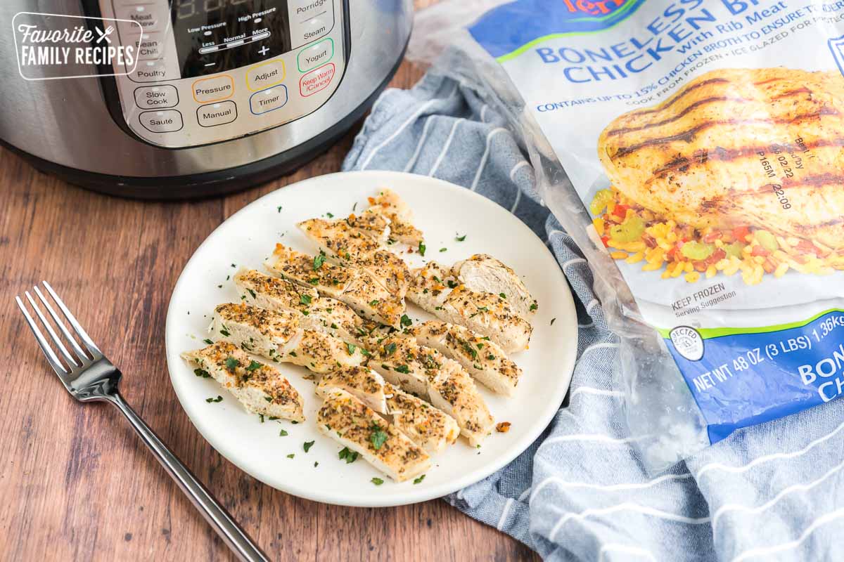 Sliced chicken on a plate with an instant pot and a bag of frozen chicken in the background