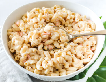 A spoon taking a scoop of Hawaiian macaroni salad from a serving bowl