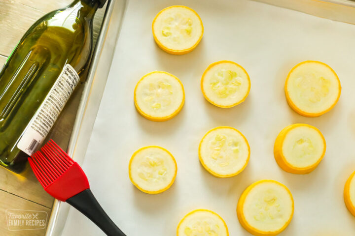  Calabaza de verano en rodajas en una bandeja para hornear con aceite de oliva listo para asar