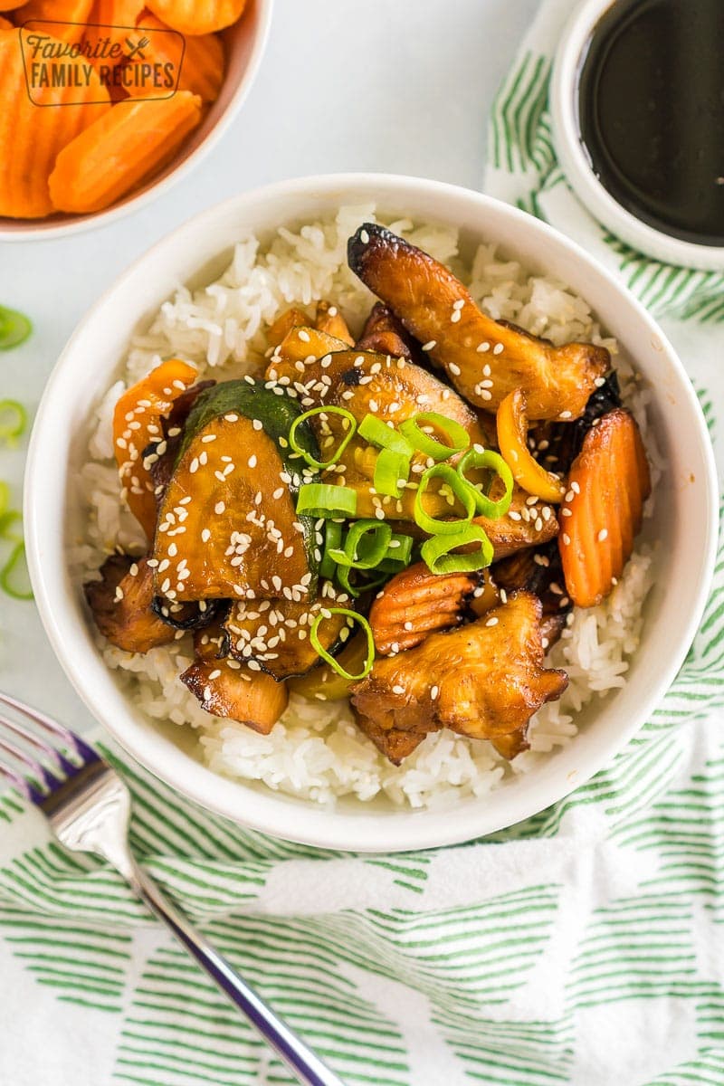 A bowl of white rice topped with chicken and vegetables