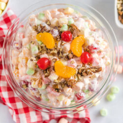 Classic ambrosia fruit salad topped with orange slices, maraschino cherries, and pecans