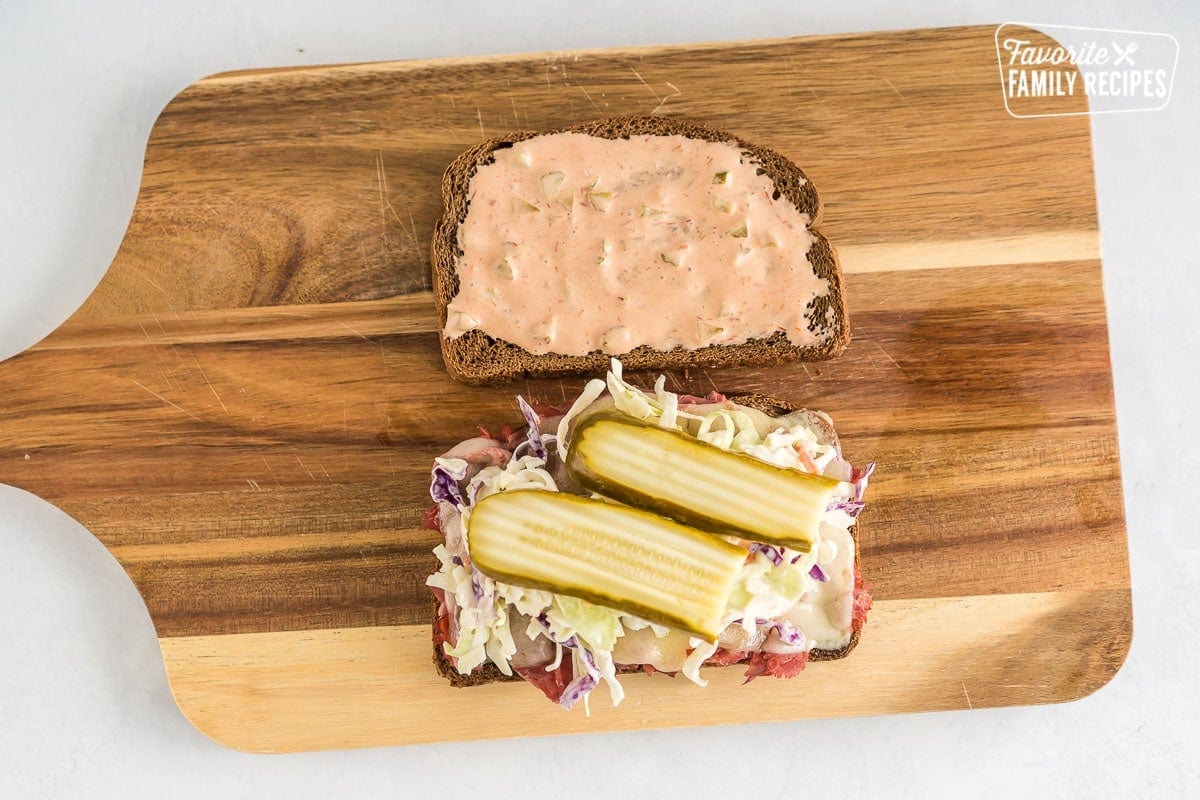 One piece of rye bread spread with Russian dressing and one piece of rye bread with corned beef, melted cheese, coleslaw, and pickles