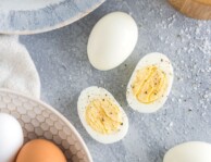 Peeled Hard Boiled Eggs on a plate with one egg cut in half and sprinkled with salt and pepper