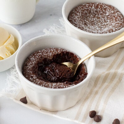 Spoon resting in a ramekin of Carnival Cruise Melting Chocolate Cake. Vanilla ice cream on the side.