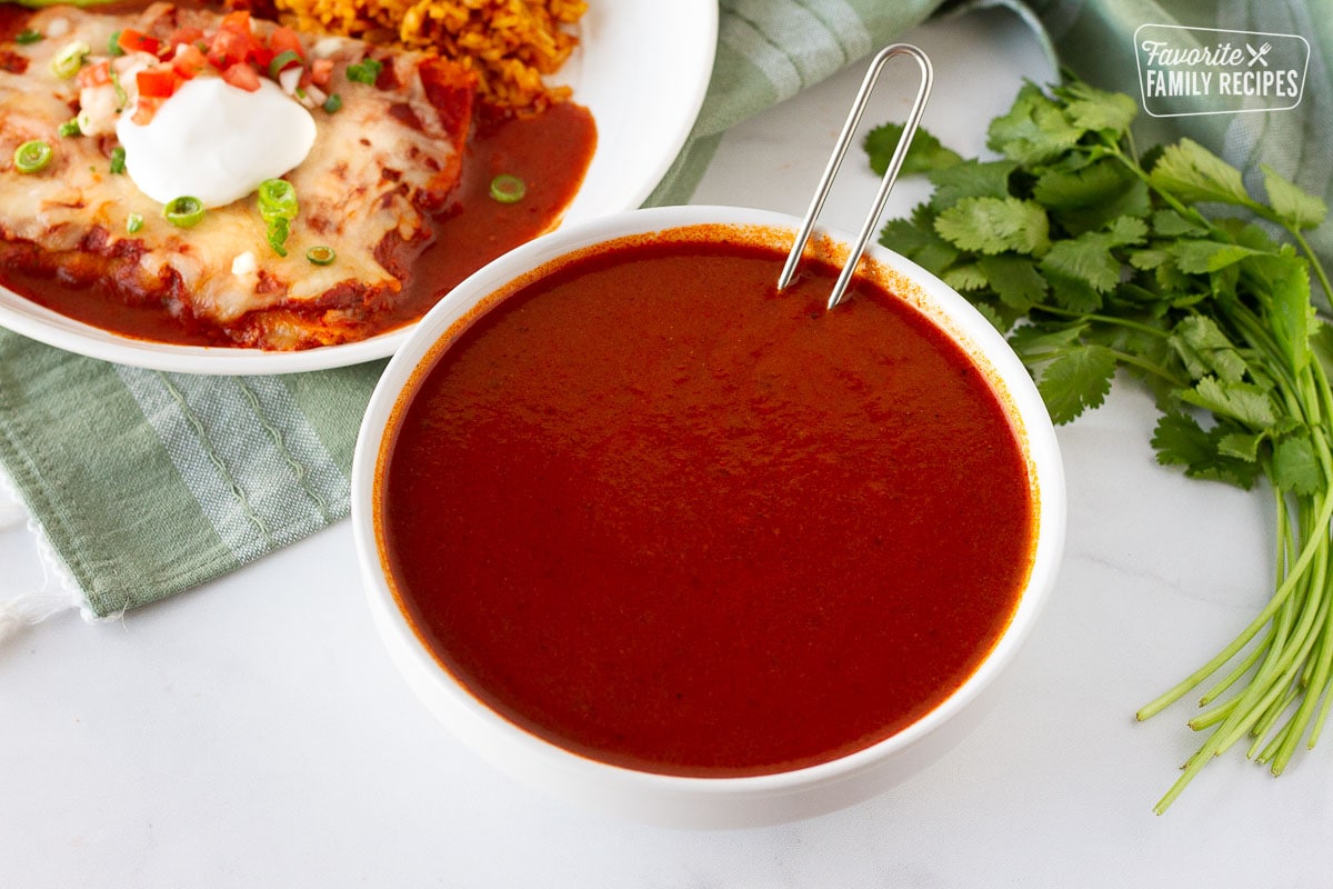 Plate of enchiladas next to a large bowl of Homemade Enchilada Sauce.