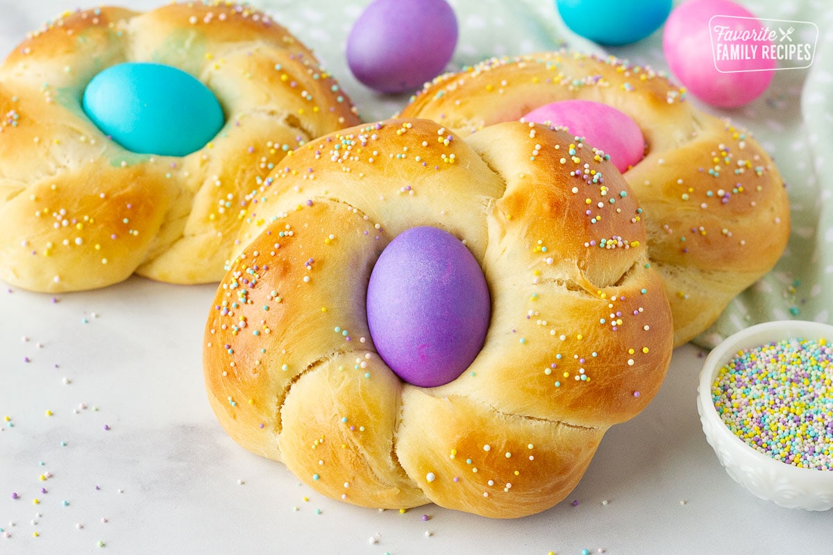 Close up view of Easter bread with a purple colored egg and sprinkles.