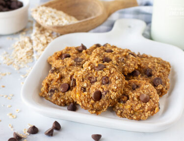 Close up of a plate of Healthy Oatmeal Cookies. Milk, oats and chocolate chips on the side.