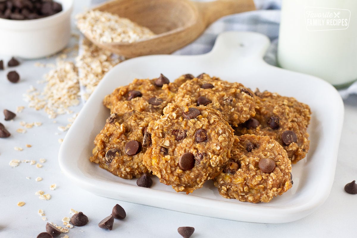 Close up of a plate of Healthy Oatmeal Cookies. Milk, oats and chocolate chips on the side.