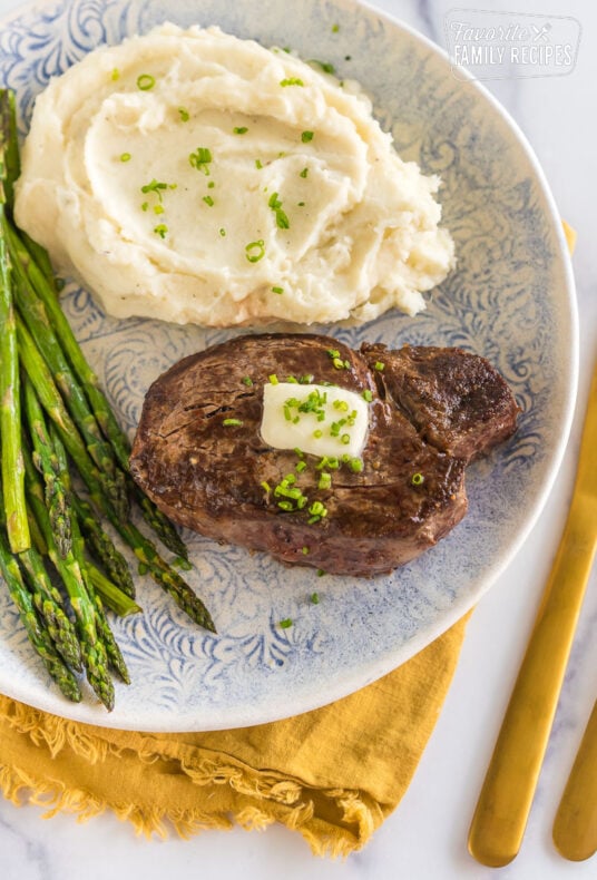 Cast iron filet mignon on a plate with mashed potatoes and asparagus