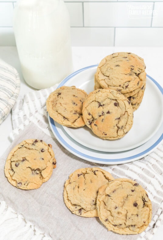 Chocolate chip cookies on a plate next to a pitcher of milk