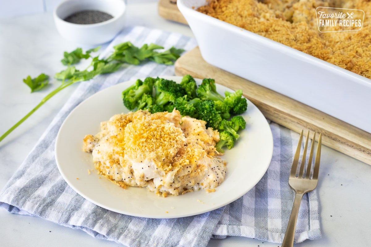 Poppy Seed Chicken on a plate with broccoli. Baking dish of Poppy Seed Chicken on the side.