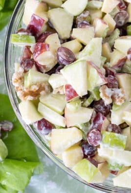 Waldorf Salad in a large glass bowl with a wooden spoon.