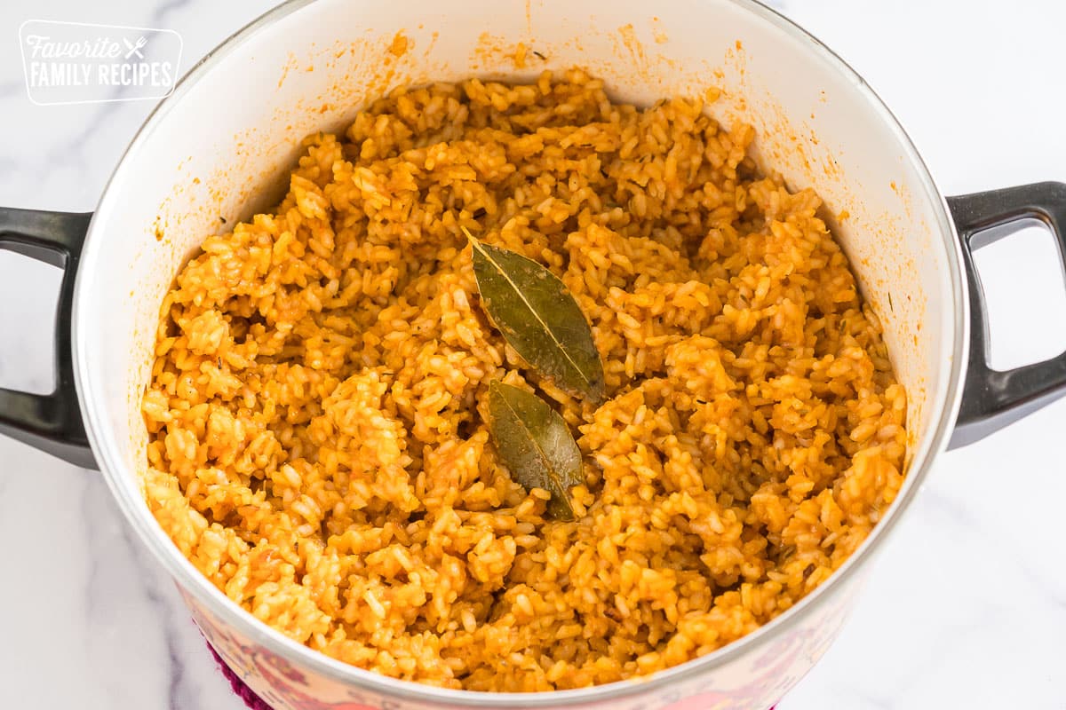 Jollof rice in a pot topped with two bay leaves.