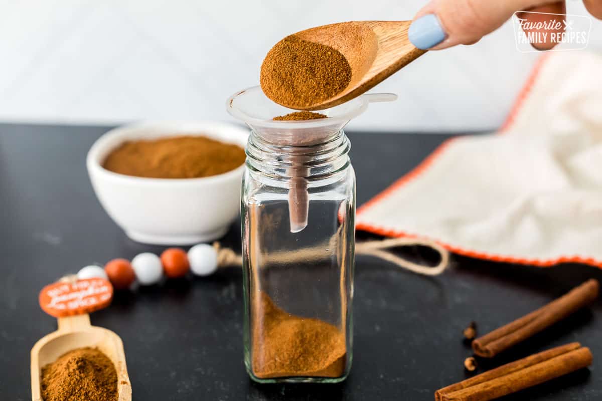 Spooning the Pumpkin Pie Spice Substitute into a glass spice jar.