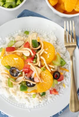 Constructed Hawaiian Haystack topped with green onion, cheese, rice noodles, green peppers, almond slices, tomatoes, celery, black olives, coconut, pineapple and mandarin oranges.