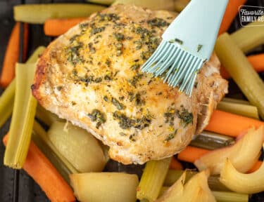 Brushing herb mixture on top of turkey breast.