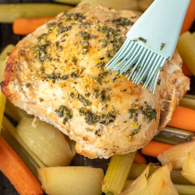 Brushing herb mixture on top of turkey breast.