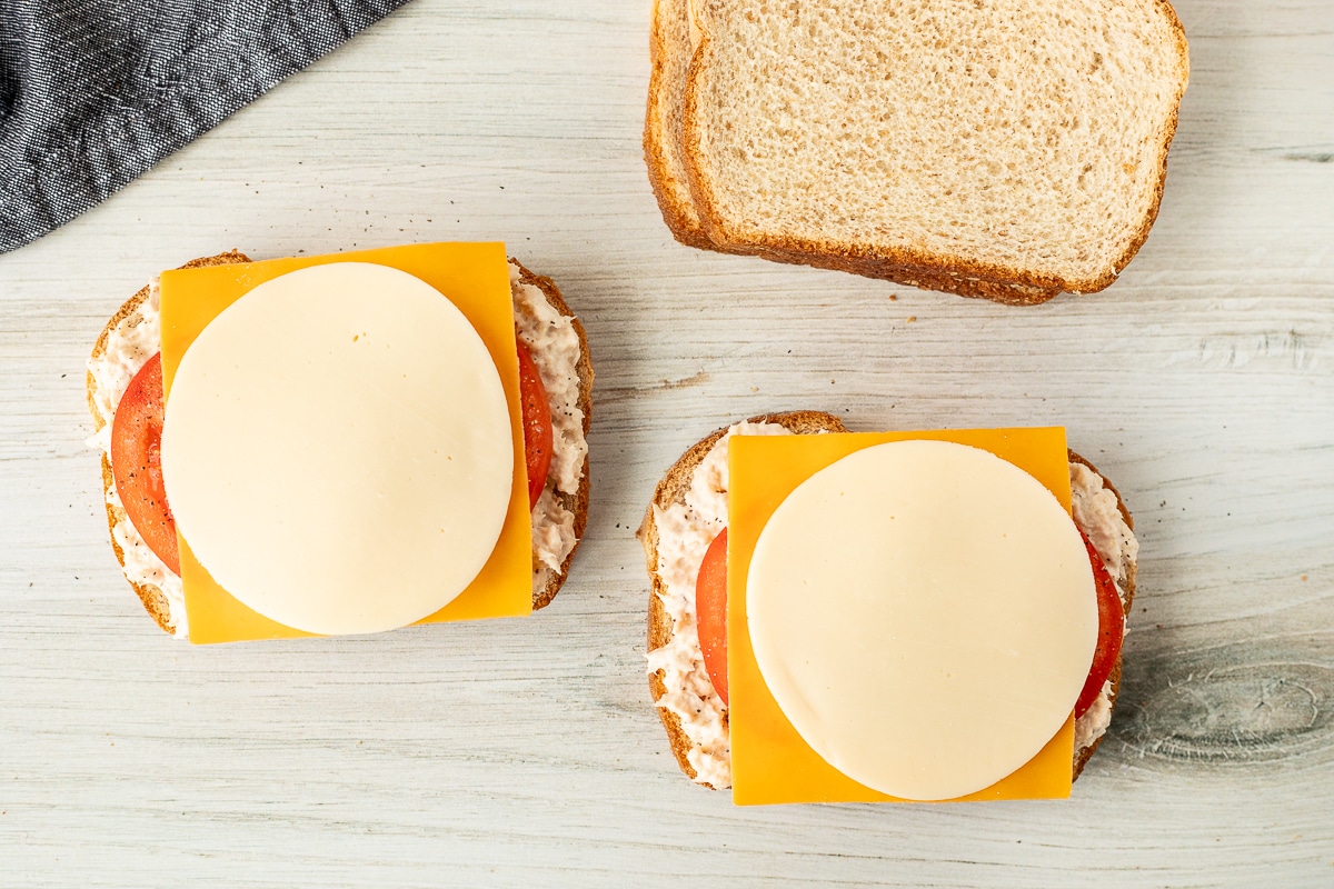 Sliced wheat bread with tuna, tomatoes and cheese.