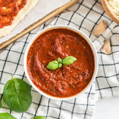 A bowl of homemade pizza sauce topped with basil leaves