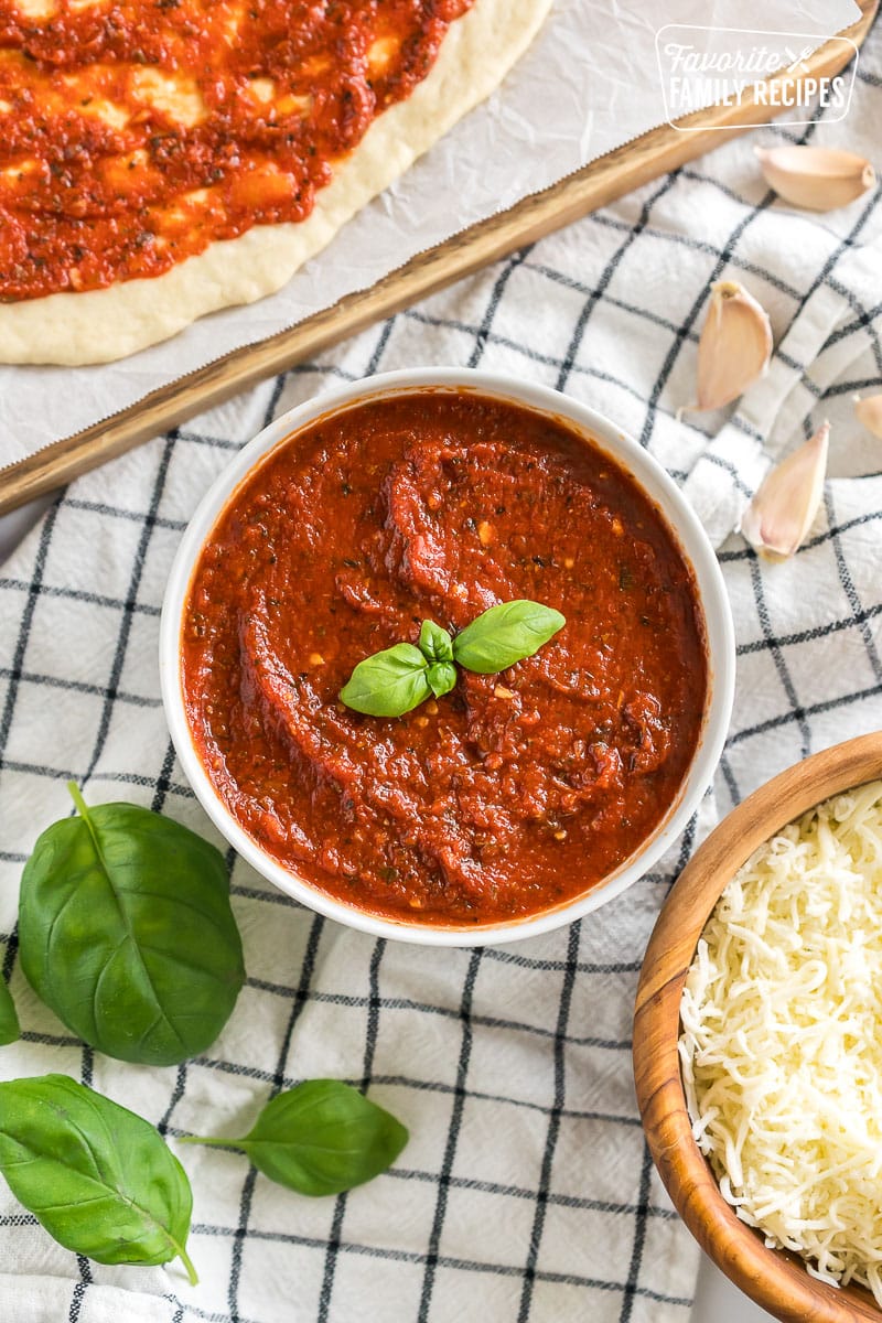 A bowl of homemade pizza sauce topped with basil leaves