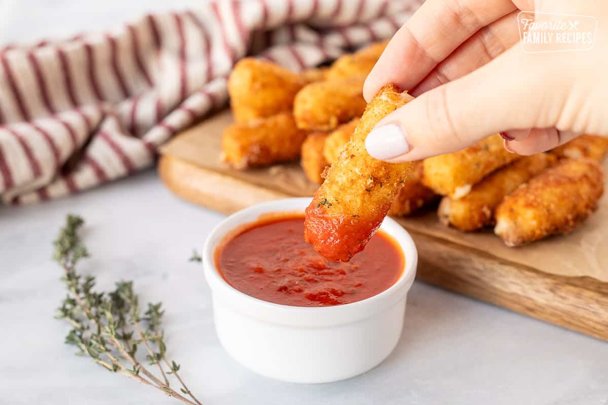 Dipping a mozzarella stick into marinara sauce.