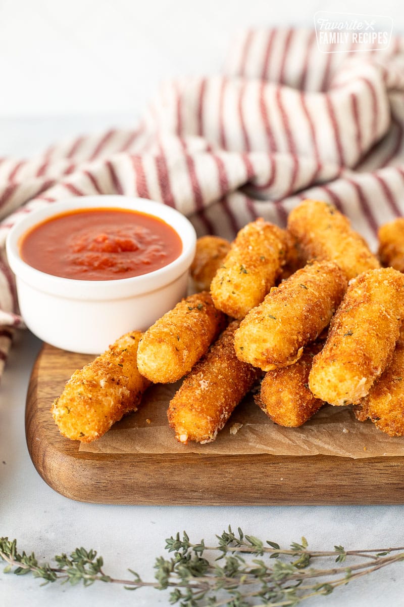 Homemade Mozzarella Sticks with cup of marinara sauce.