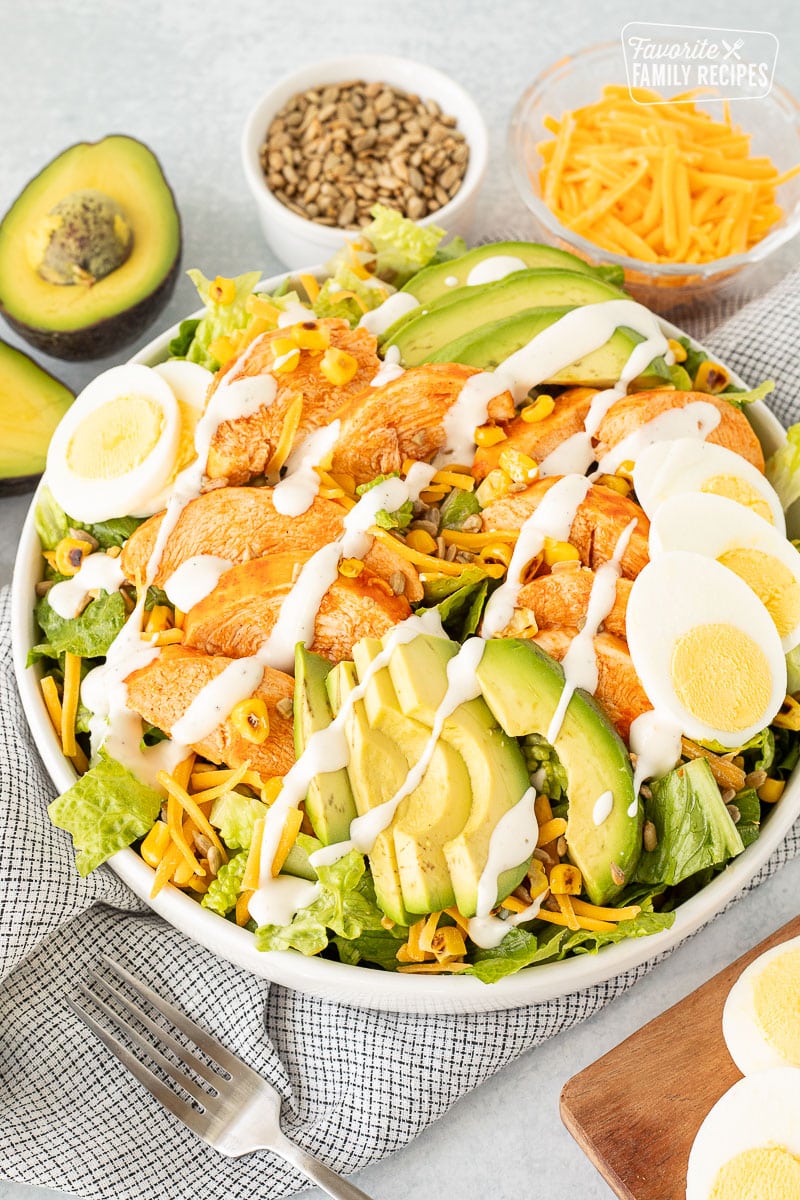 Buffalo Chicken Salad in a bowl with chicken breast, avocado, egg, corn and sunflower seeds.